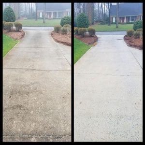 A side-by-side comparison shows a concrete driveway before and after cleaning. On the left, the driveway is dirty and discolored, while on the right, it appears clean and bright. The background features neatly trimmed bushes and trees with houses in the distance.