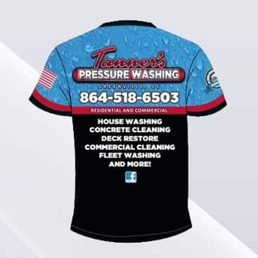 A black and blue shirt for "Tanner's Pressure Washing" displaying their logo, contact number 864-518-6503, and services such as house washing, concrete cleaning, deck restoration, commercial cleaning, and fleet washing. An American flag is on the left sleeve.