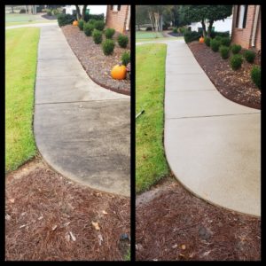 Side-by-side comparison of a concrete pathway bordered by grass. The left image shows the pathway dirty and stained, while the right image displays the same pathway clean and bright after power washing. A neatly trimmed shrub bed with pumpkins is visible along the path.